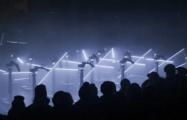 Dorna robots in CODA - a stage performance by Collectif Scale, where the robots are using lights to create visual aesthetics - which the audience are watching. 